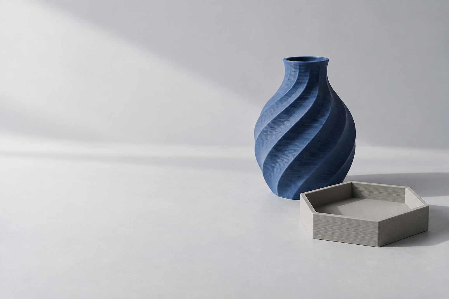 A blue 3D printed vase and tray, showing the fine layers of their surfaces.